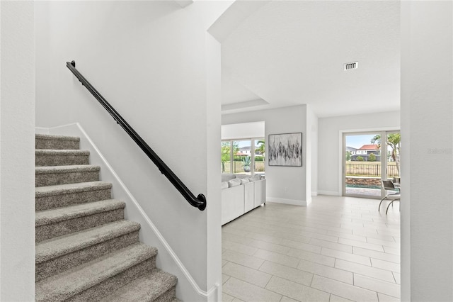 staircase featuring baseboards, plenty of natural light, and visible vents
