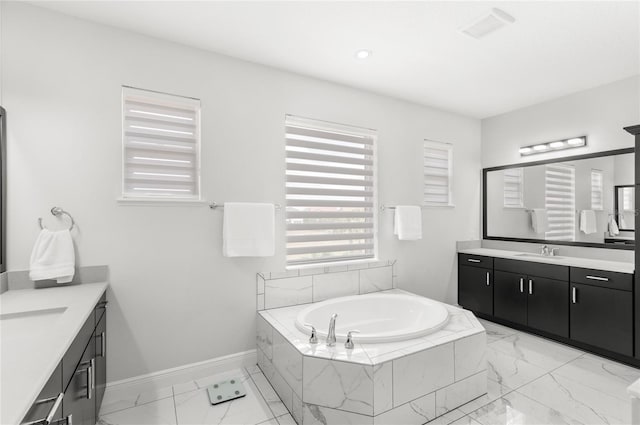 bathroom with a bath, two vanities, a sink, and marble finish floor