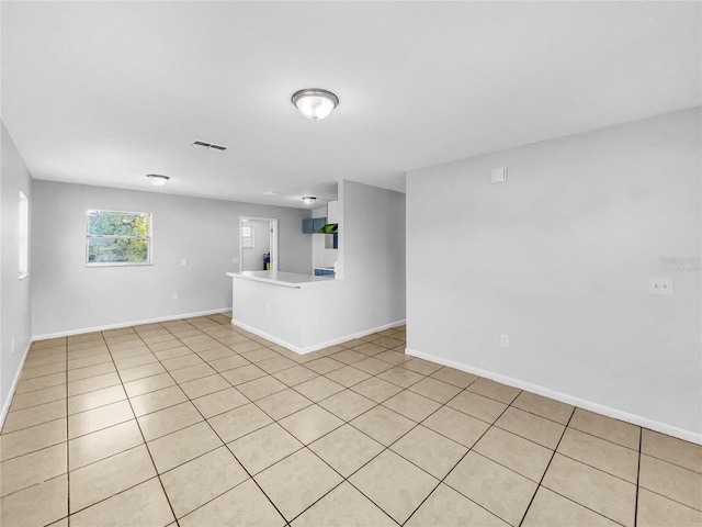 empty room with light tile patterned floors, visible vents, and baseboards