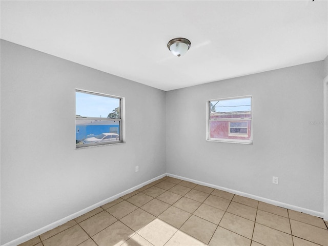 spare room featuring baseboards, light tile patterned floors, and a healthy amount of sunlight