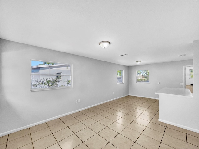 empty room featuring light tile patterned flooring, visible vents, and baseboards