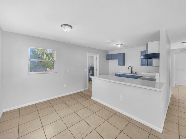 kitchen with water heater, light tile patterned floors, light countertops, a sink, and a peninsula