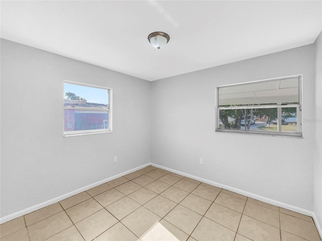 unfurnished room with light tile patterned floors and baseboards