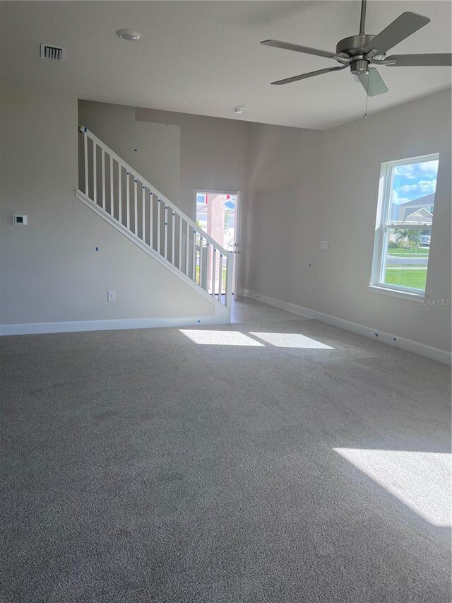 unfurnished living room featuring baseboards, carpet, a ceiling fan, and visible vents