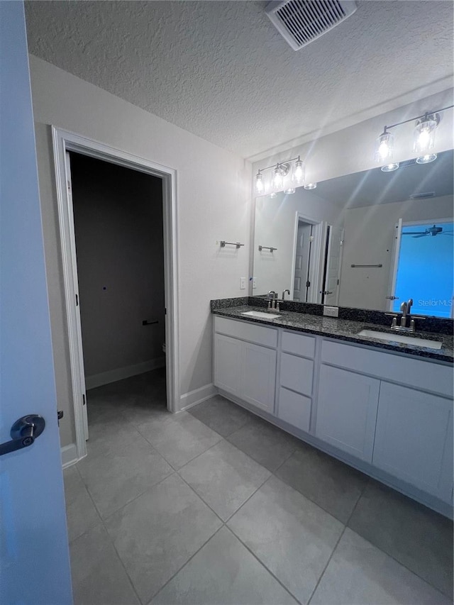 full bathroom featuring double vanity, a textured ceiling, visible vents, tile patterned flooring, and a sink