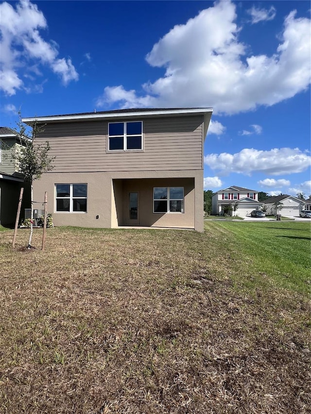 rear view of house featuring stucco siding and a yard