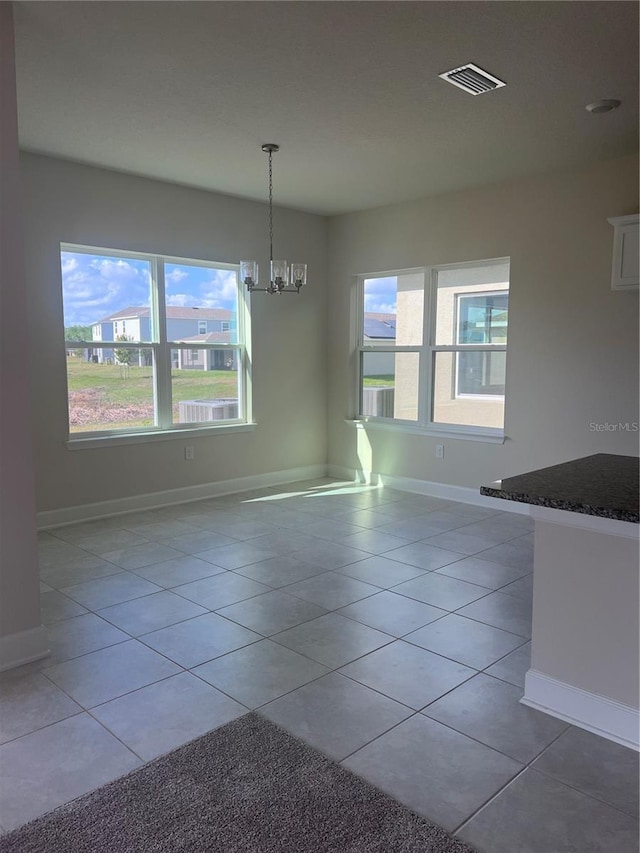 unfurnished dining area featuring light tile patterned flooring, a chandelier, and a wealth of natural light