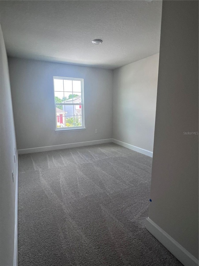 carpeted empty room featuring baseboards and a textured ceiling