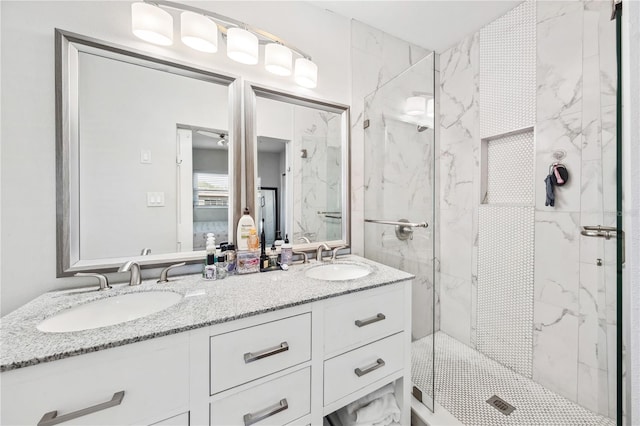 full bath featuring double vanity, a marble finish shower, and a sink