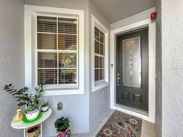 entrance to property featuring stucco siding and covered porch