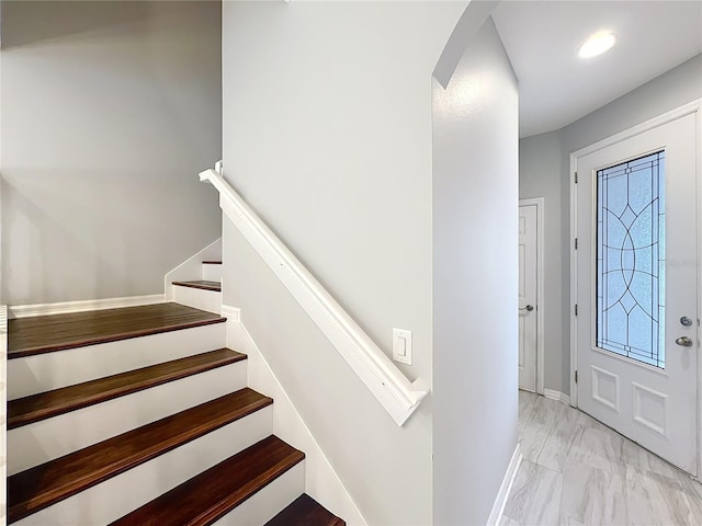 foyer featuring marble finish floor, arched walkways, stairway, and baseboards