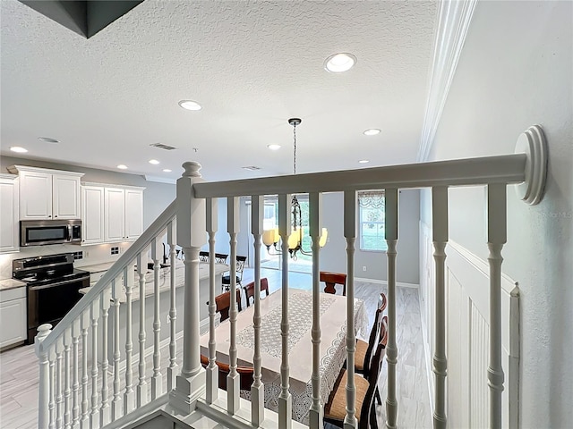 staircase featuring a textured ceiling, visible vents, recessed lighting, and ornamental molding