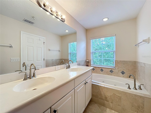 full bathroom featuring a tub with jets, visible vents, double vanity, and a sink