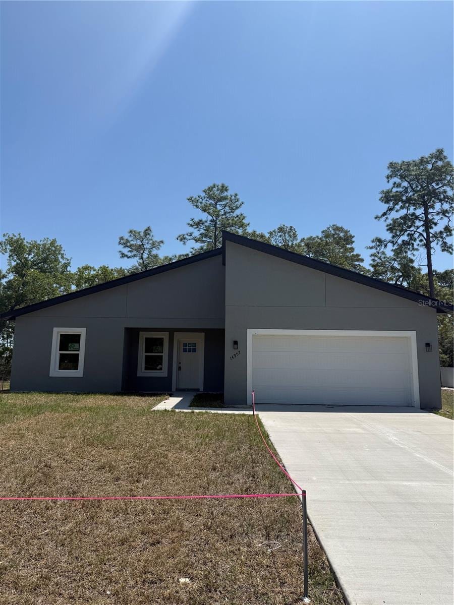 contemporary home with driveway, a front yard, stucco siding, and an attached garage