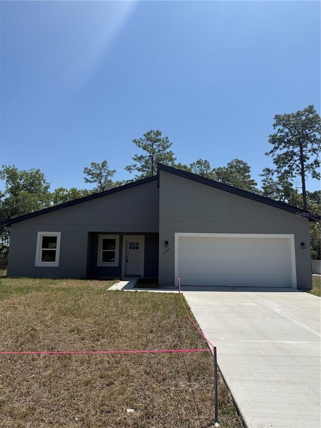 contemporary home with driveway, a front yard, stucco siding, and an attached garage