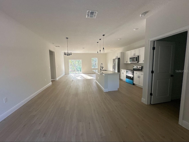 14957 SW 63rd Court Rd, Ocala, FL 34473 - kitchen with appliances with stainless steel finishes, a kitchen island with sink, white cabinets, light wood finished floors, and open floor plan