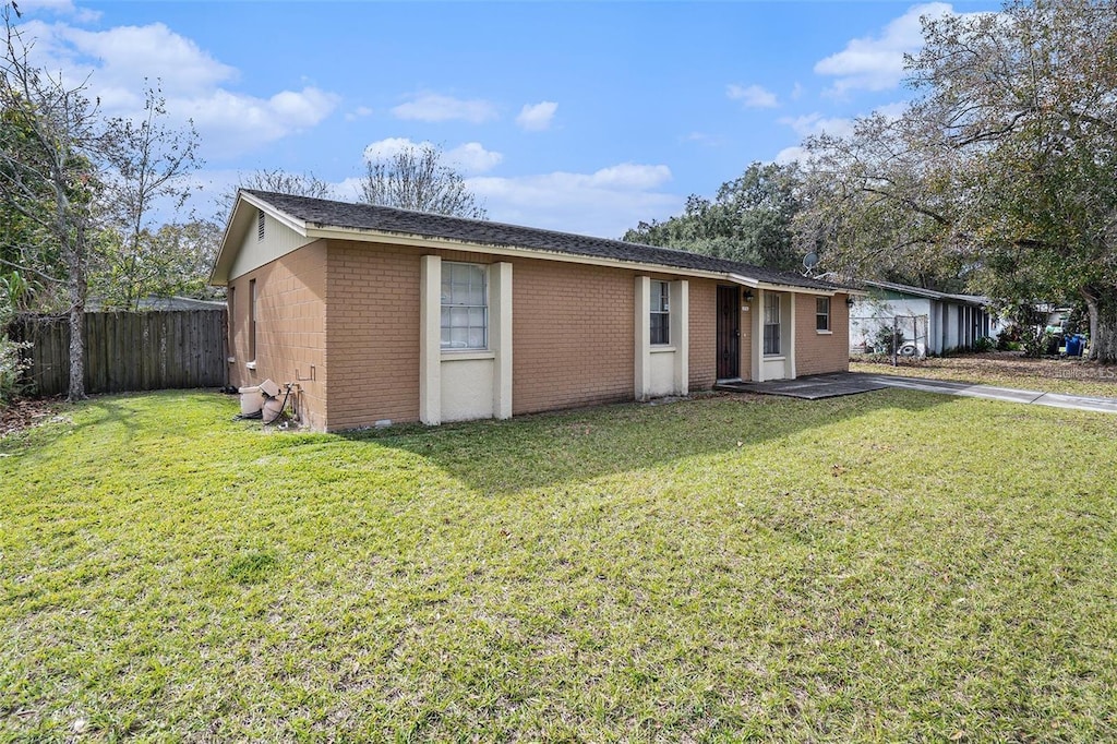 ranch-style house with brick siding, a front lawn, and fence