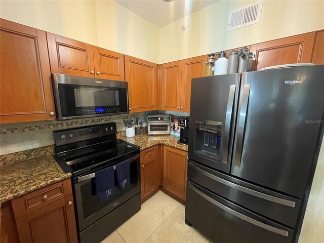 20310 Estero Gardens Cir Unit 203, Estero, FL 33928 - kitchen featuring black appliances, tasteful backsplash, dark stone counters, and brown cabinetry