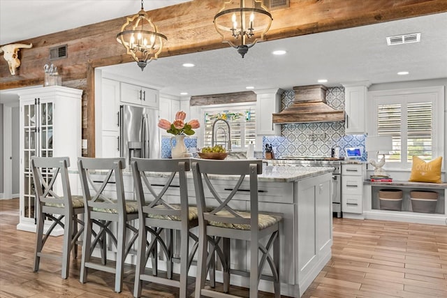 2105 Fosgate Dr, Winter Park, FL 32789 - kitchen with light wood-type flooring, visible vents, custom exhaust hood, and appliances with stainless steel finishes