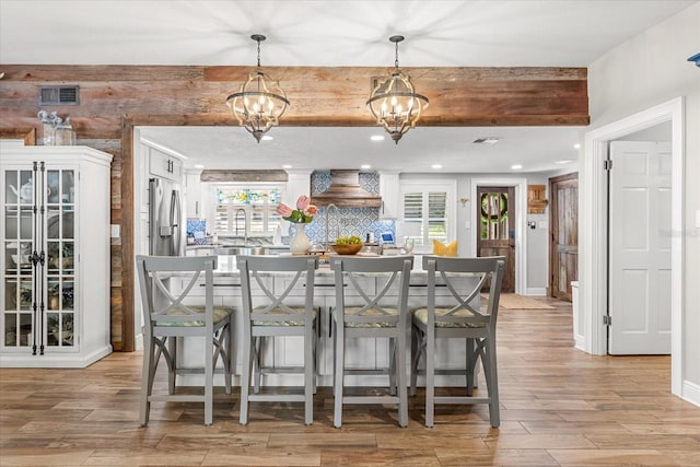 2105 Fosgate Dr, Winter Park, FL 32789 - bar with custom range hood, light wood finished floors, visible vents, stainless steel refrigerator with ice dispenser, and a notable chandelier
