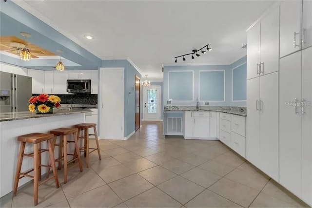 kitchen with light tile patterned flooring, appliances with stainless steel finishes, rail lighting, white cabinetry, and tasteful backsplash