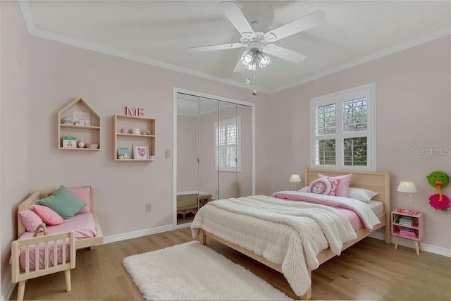 bedroom featuring crown molding, baseboards, wood finished floors, and a closet