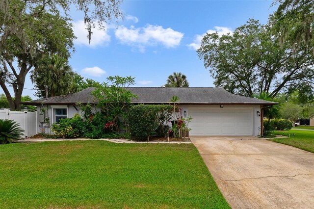single story home featuring concrete driveway, an attached garage, fence, and a front yard