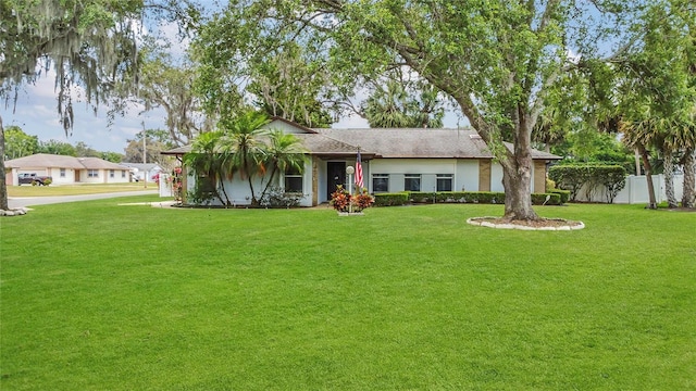 ranch-style house featuring fence and a front yard