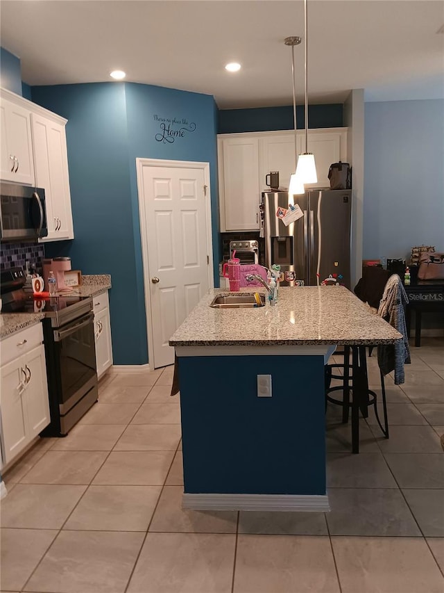 kitchen with a breakfast bar area, appliances with stainless steel finishes, tasteful backsplash, a sink, and white cabinetry