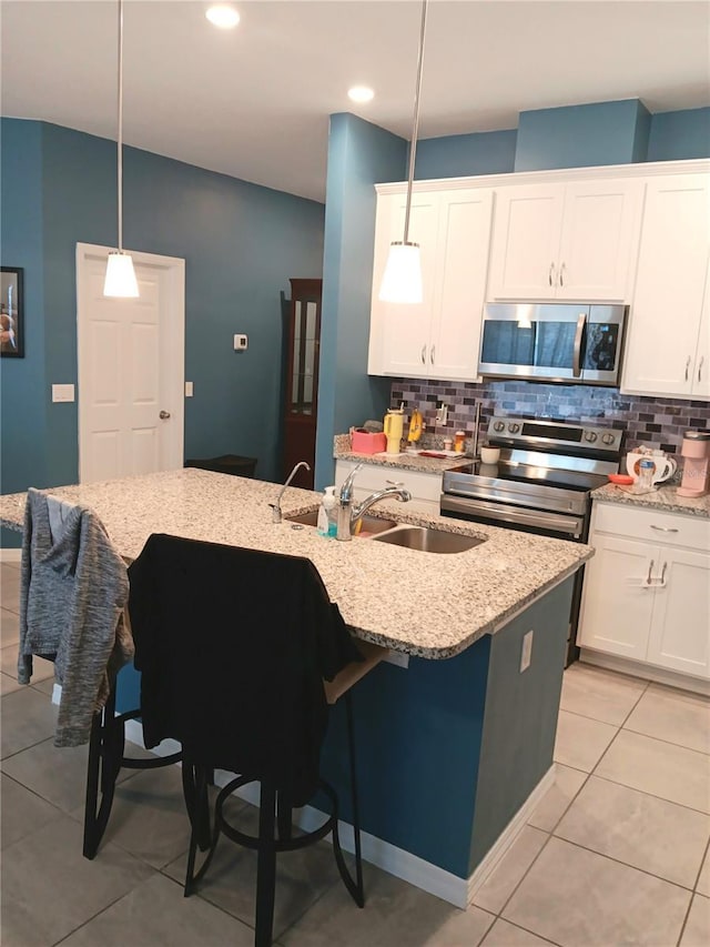 kitchen featuring backsplash, appliances with stainless steel finishes, pendant lighting, and a sink