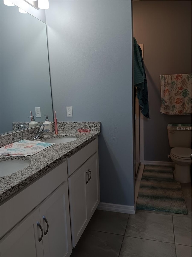 bathroom featuring double vanity, toilet, tile patterned floors, and a sink