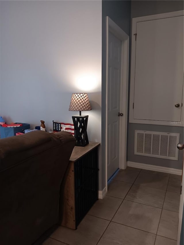 corridor with baseboards, visible vents, and light tile patterned floors
