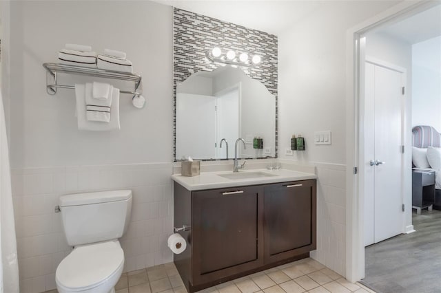 225 Celebration Pl Unit 401, Kissimmee, FL 34747 - bathroom featuring tile walls, a wainscoted wall, vanity, toilet, and tile patterned flooring