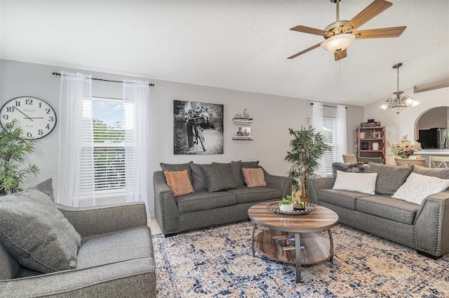 living area with ceiling fan with notable chandelier and lofted ceiling