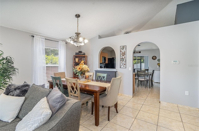 dining room featuring plenty of natural light, arched walkways, light tile patterned floors, and a chandelier