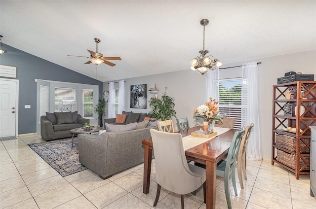 dining space with vaulted ceiling, light tile patterned floors, and ceiling fan with notable chandelier