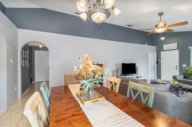 tiled dining room with arched walkways, high vaulted ceiling, a textured ceiling, ceiling fan with notable chandelier, and visible vents