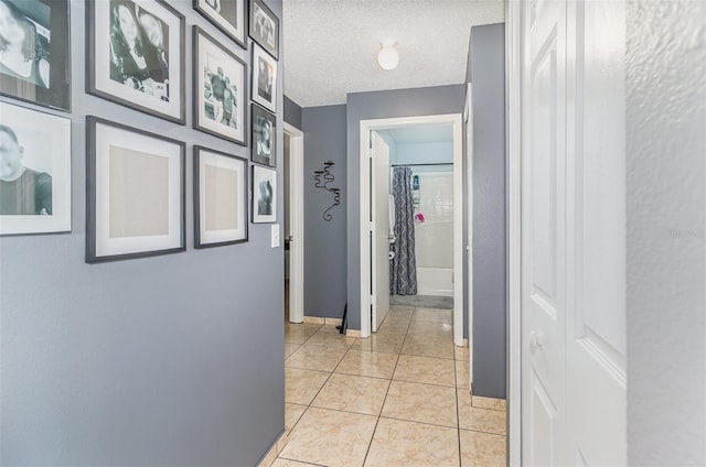 corridor with a textured ceiling and light tile patterned floors