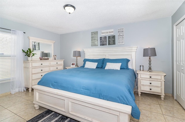 bedroom with light tile patterned floors, baseboards, a closet, and a textured ceiling