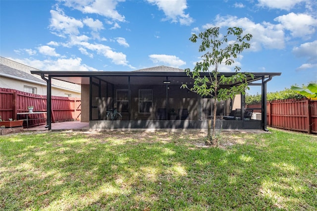 rear view of property featuring a lawn, a sunroom, and a fenced backyard
