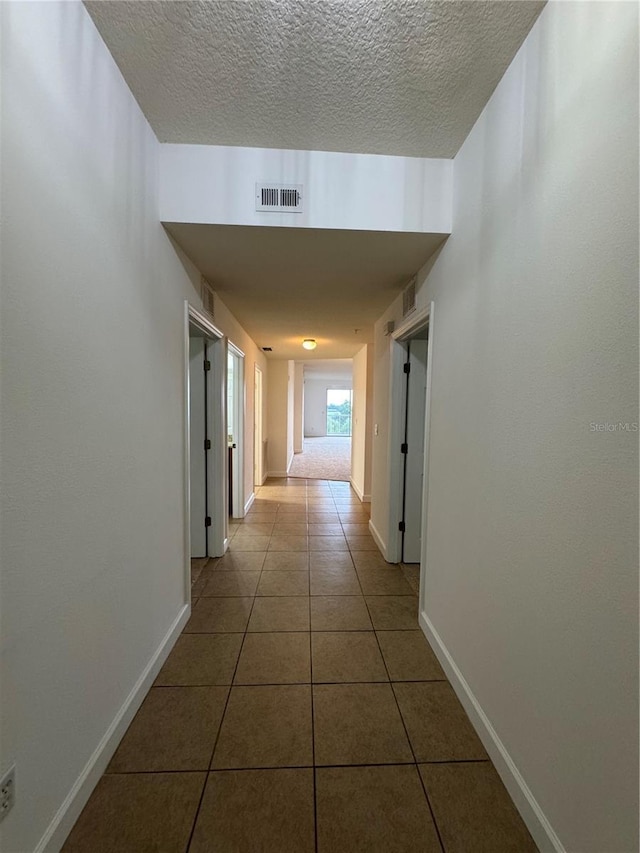 6336 Buford St Unit 307, Orlando, FL 32835 - hall featuring tile patterned floors, baseboards, a textured ceiling, and visible vents