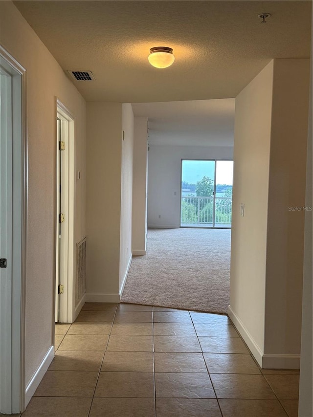 6336 Buford St Unit 307, Orlando, FL 32835 - hallway with a textured ceiling, visible vents, tile patterned flooring, carpet floors, and baseboards