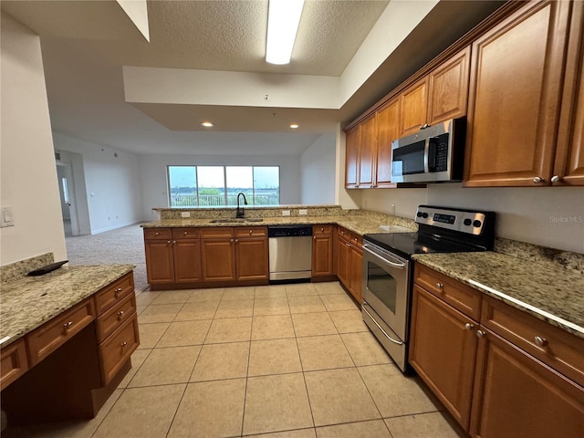 6336 Buford St Unit 307, Orlando, FL 32835 - kitchen featuring a sink, appliances with stainless steel finishes, light stone countertops, and brown cabinetry