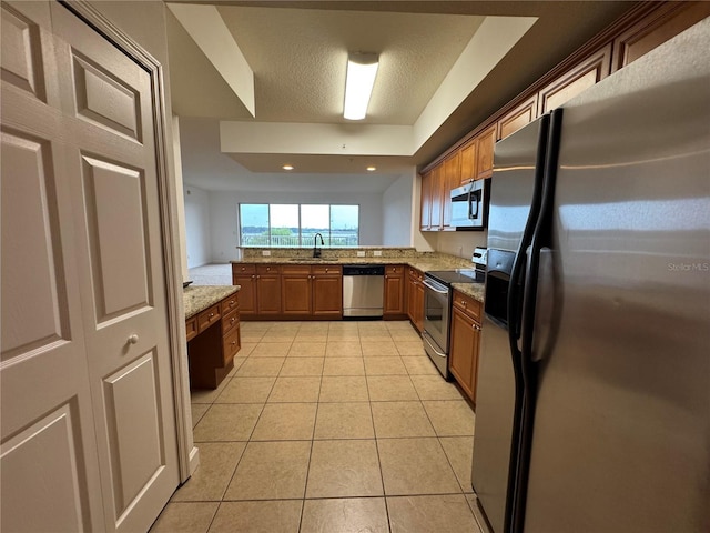 6336 Buford St Unit 307, Orlando, FL 32835 - kitchen featuring light tile patterned flooring, brown cabinets, light stone counters, a sink, and stainless steel appliances