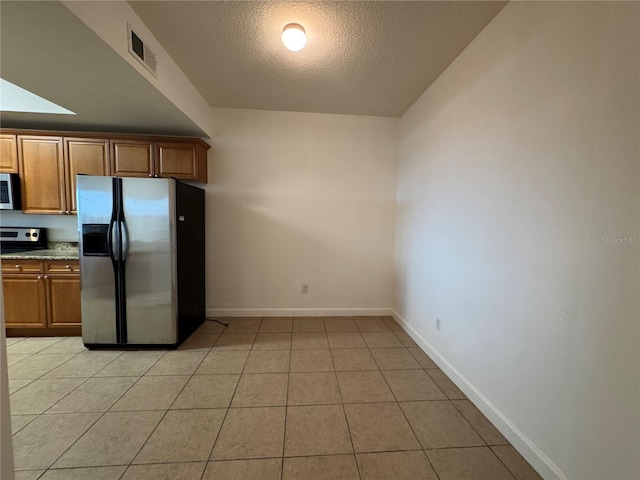 6336 Buford St Unit 307, Orlando, FL 32835 - kitchen featuring brown cabinets, appliances with stainless steel finishes, a textured ceiling, baseboards, and visible vents