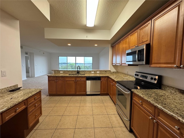 6336 Buford St Unit 307, Orlando, FL 32835 - kitchen with brown cabinets, light stone counters, a sink, stainless steel appliances, and a peninsula