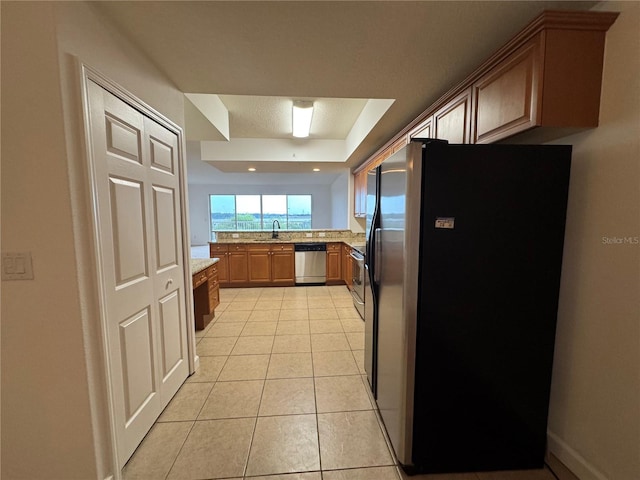 6336 Buford St Unit 307, Orlando, FL 32835 - kitchen with light stone countertops, a sink, stainless steel appliances, light tile patterned floors, and a tray ceiling