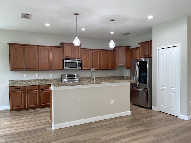 5839 Tarleton Way, Mount Dora, FL 32757 - kitchen with appliances with stainless steel finishes, light wood-style flooring, hanging light fixtures, light stone countertops, and an island with sink