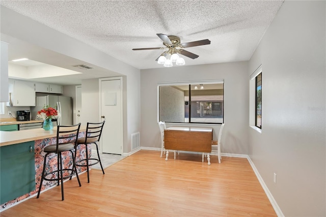 kitchen with ceiling fan, freestanding refrigerator, light wood-type flooring, and visible vents