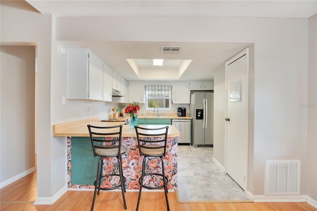 kitchen with light countertops, stainless steel appliances, visible vents, and a peninsula